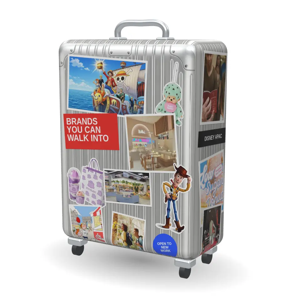 A silver suitcase covered in project stickers